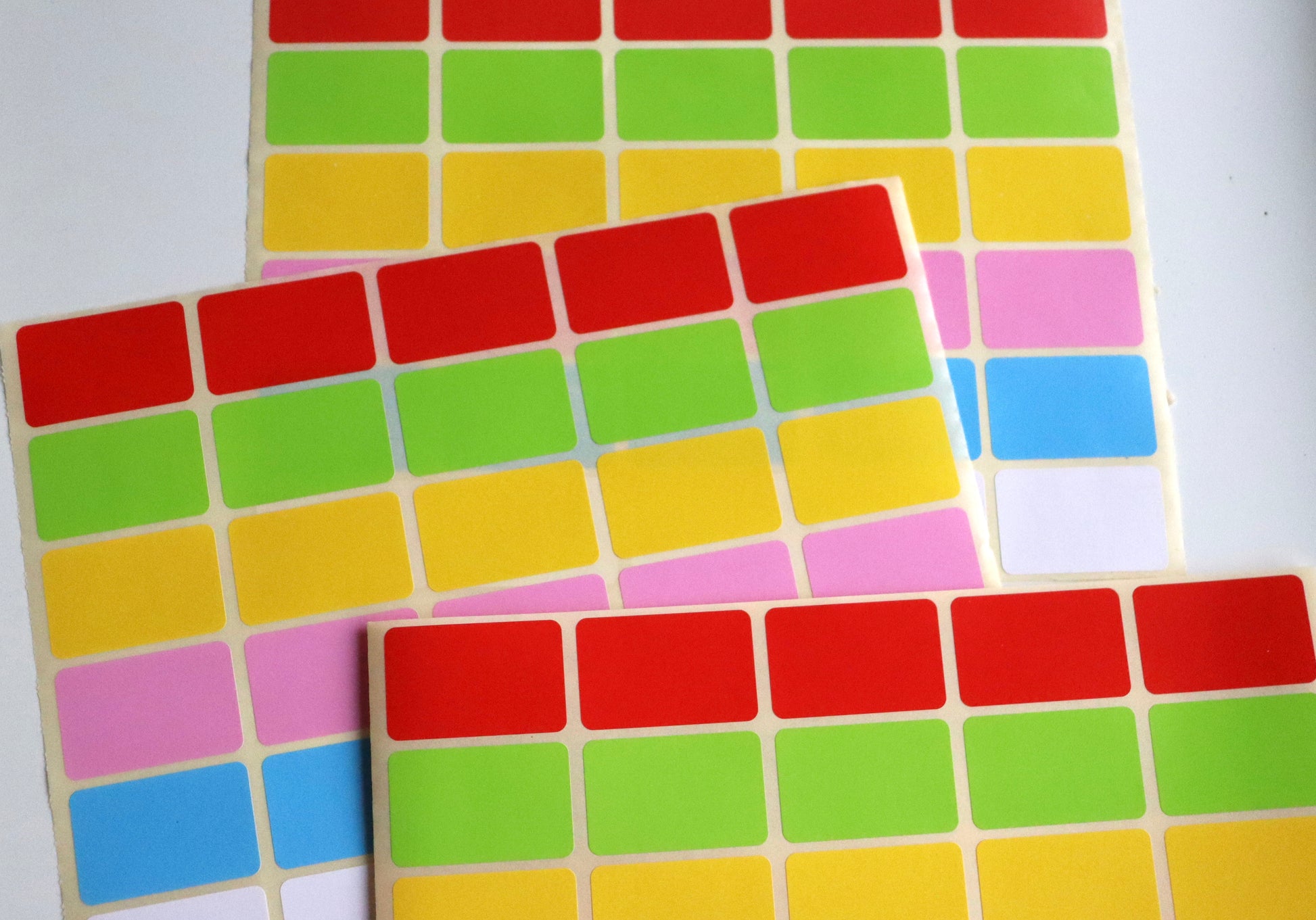 Three sheets of small, rectangular colorful stickers in red, green, yellow, pink, and blue.