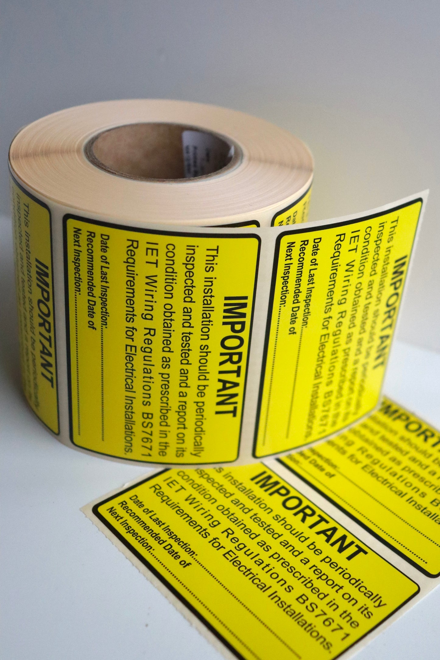 Multiple BS7671 Periodic Test Inspection Labels on roll, 76×52mm yellow electrical safety stickers.